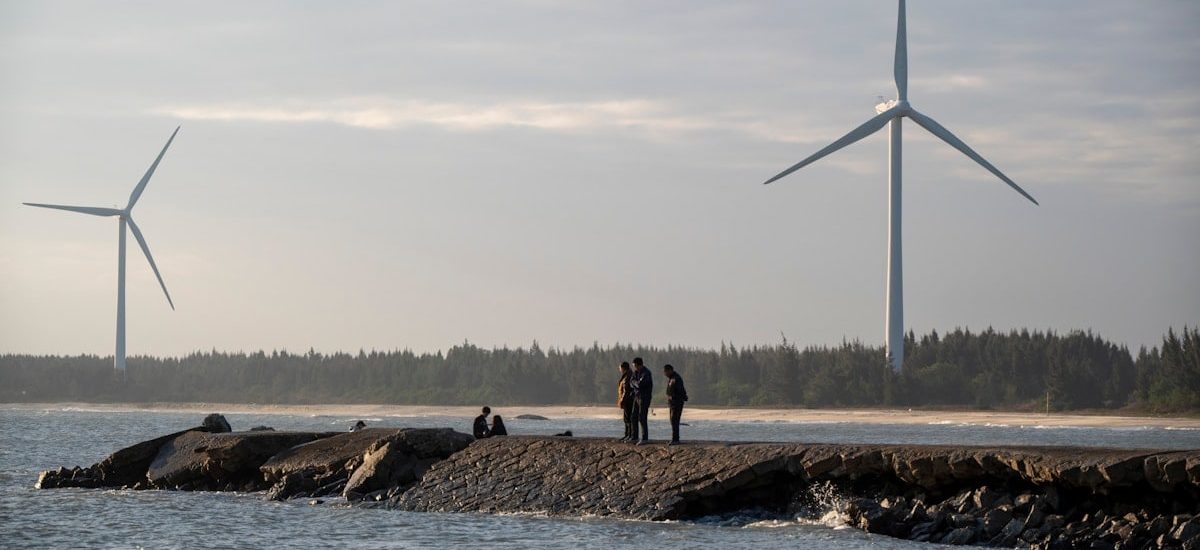 A group of people standing on a rock near a body of water