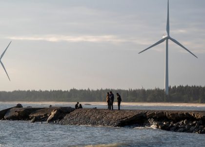 A group of people standing on a rock near a body of water